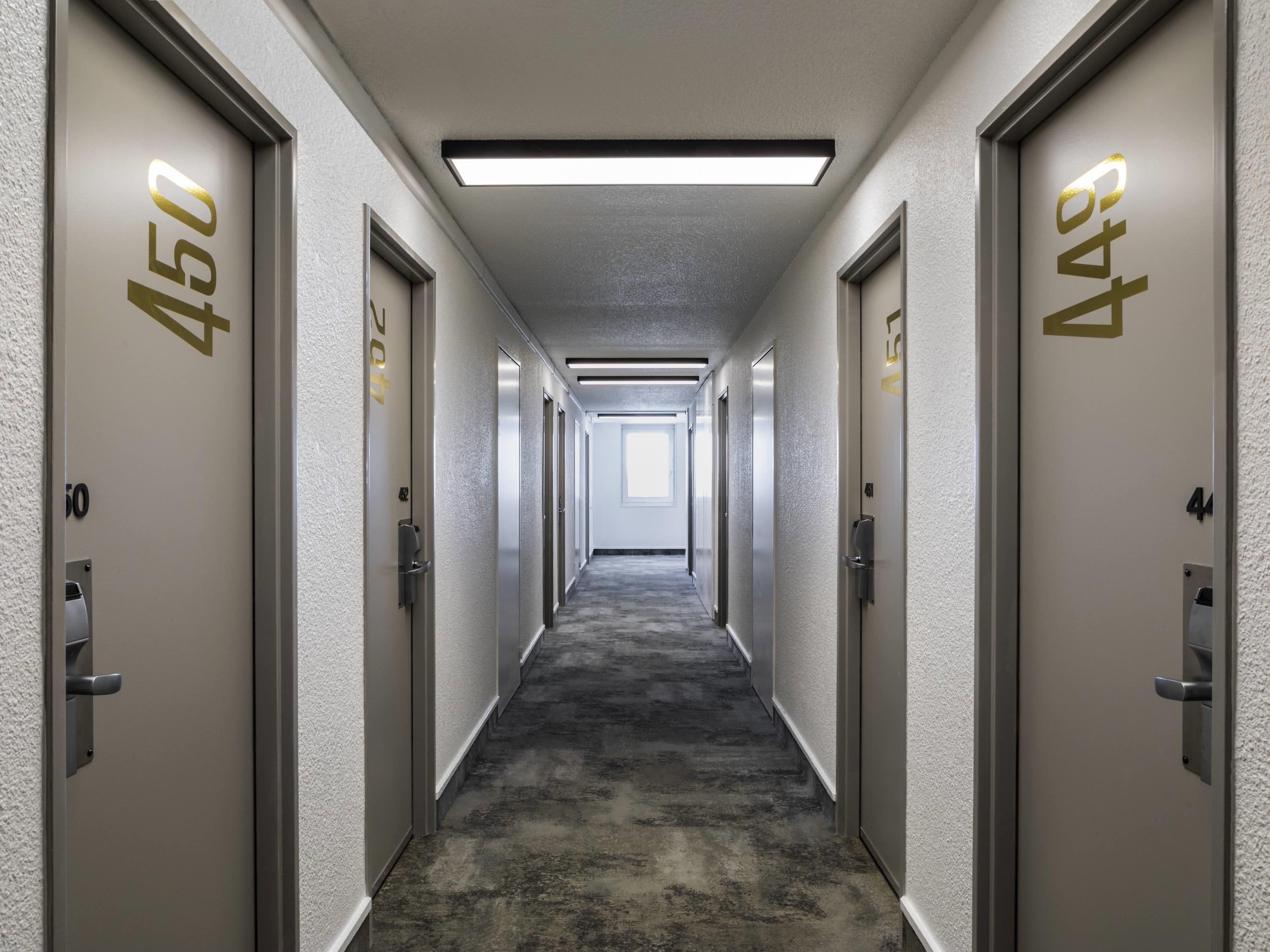 A hallway with doors labeled 450 and 454, carpeted floors, and a ceiling light.