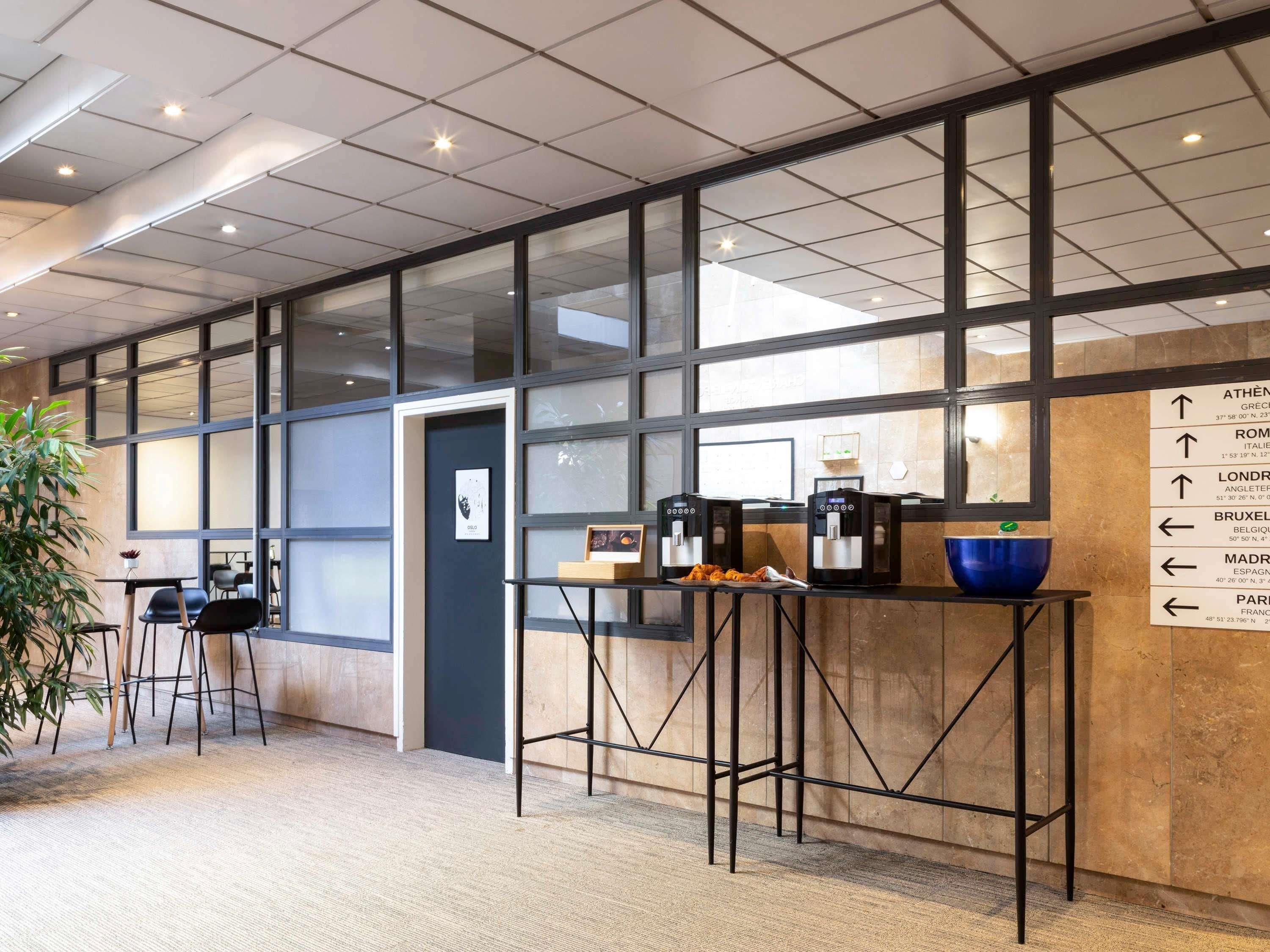 Een modern interieur met een koffiehoek, bewegwijzering en een groot raam.