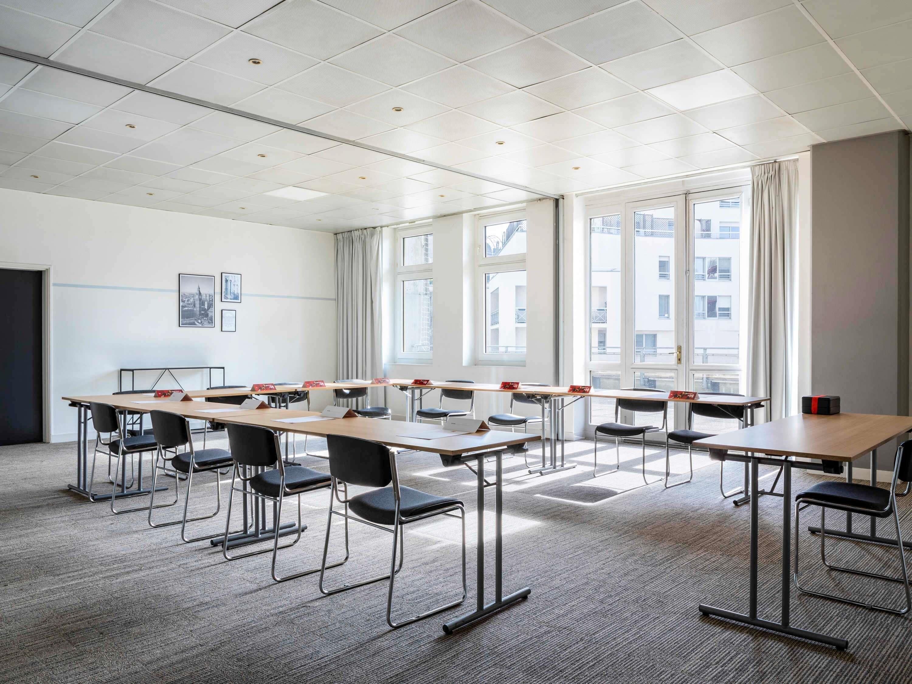 A conference room with a long table, chairs, and large windows.