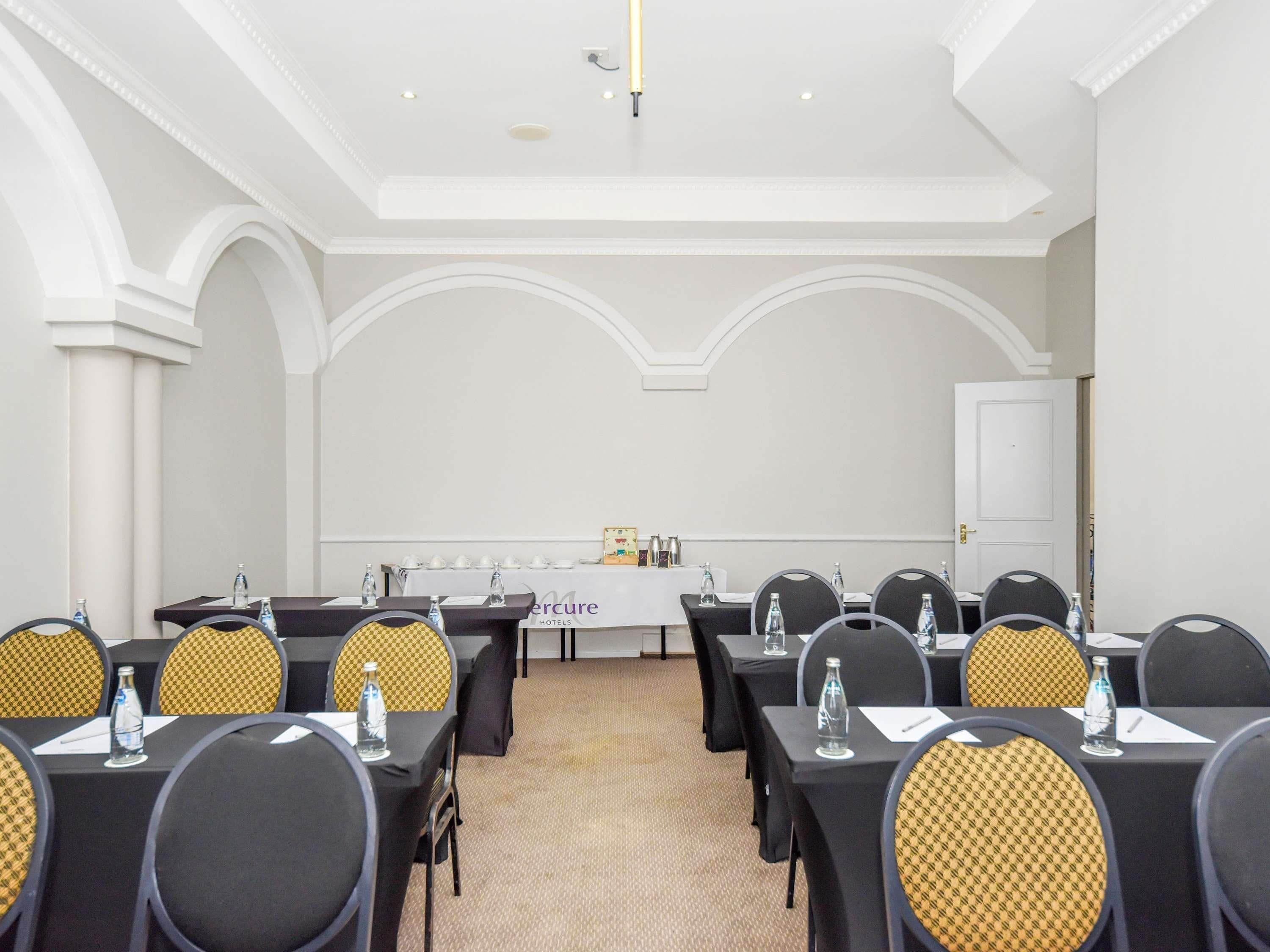 A conference room with tables and chairs, a whiteboard, and a door.