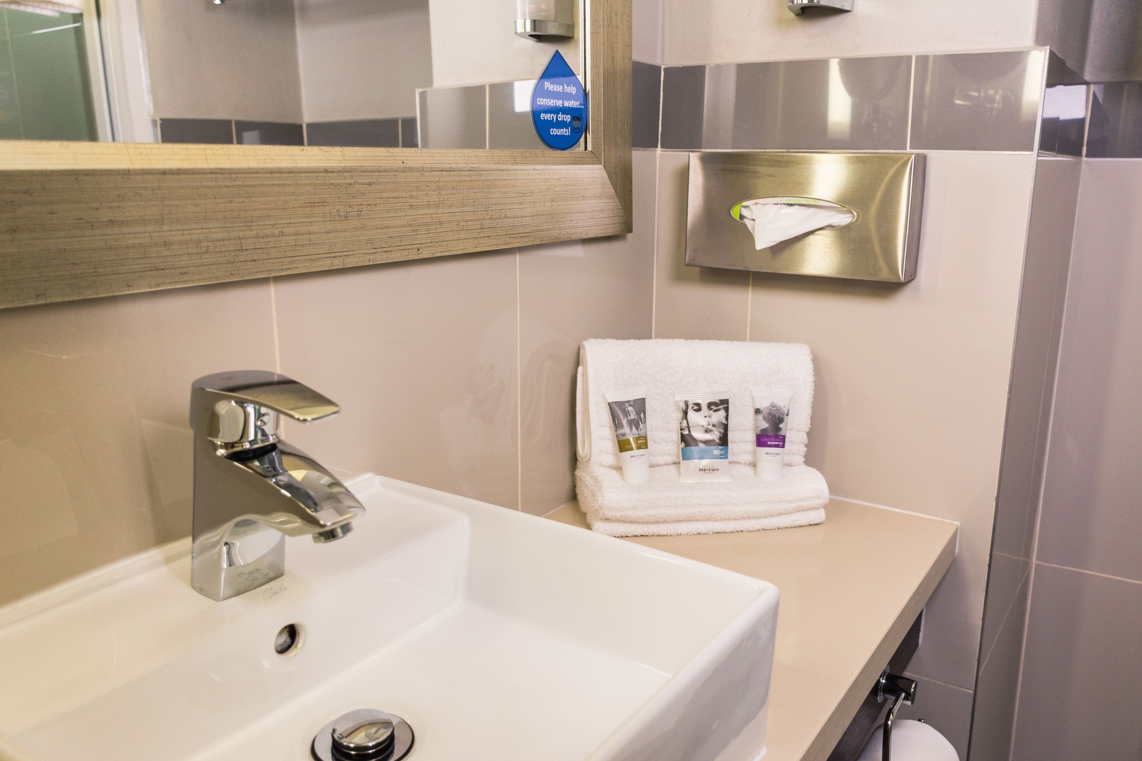 A bathroom with a white sink, a mirror, a towel rack with a folded towel, and a hand dryer.