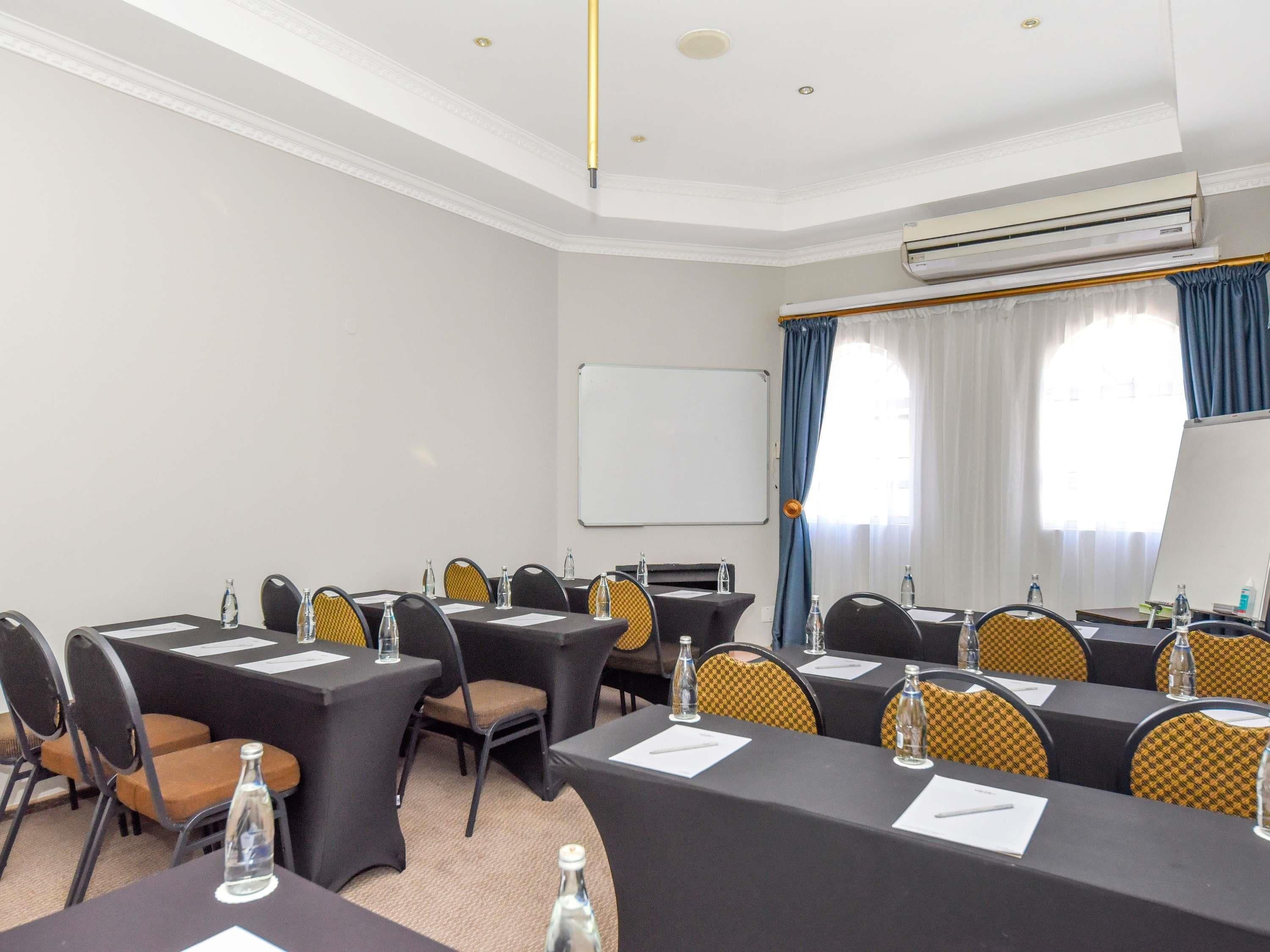 A conference room with tables, chairs, a whiteboard, and an air conditioning unit.