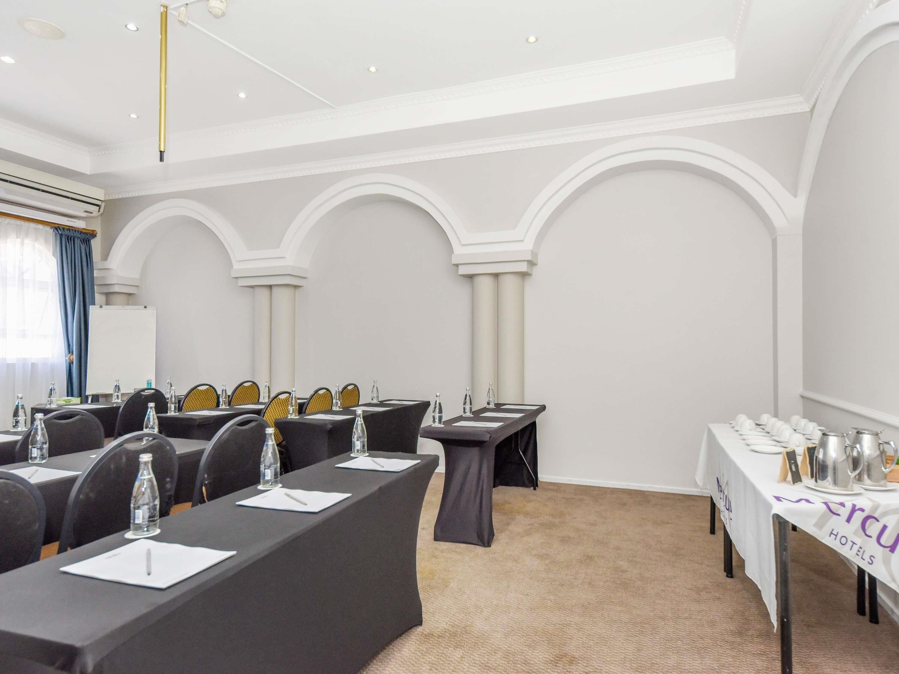 A conference room with tables, chairs, and a whiteboard.