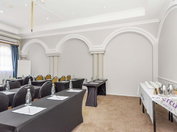 A conference room with tables, chairs, and a whiteboard.