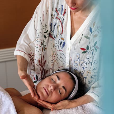 A person receiving a massage in a room with a plain wall and a white towel.