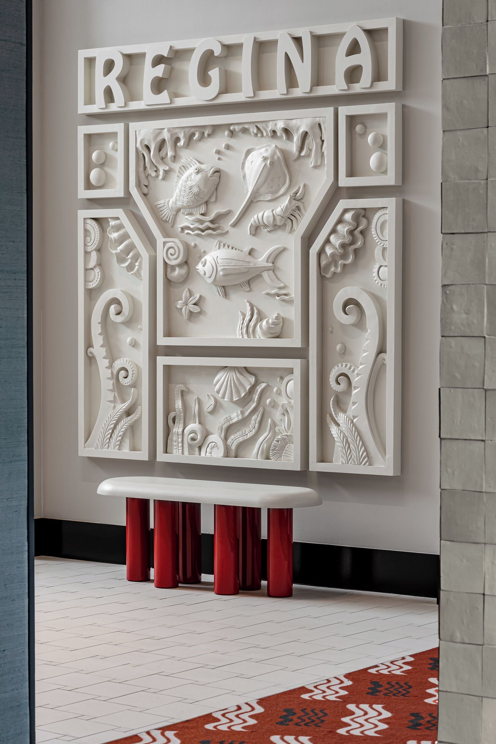 A wall with the word "REGINA" and decorative reliefs of fish and sea life.