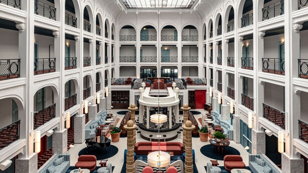 A multi-level hotel lobby with a central seating area, multiple balconies, and a high ceiling with skylights. - Regina Experimental Biarritz (Biarritz)
