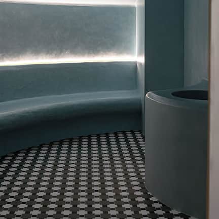 A modern bathroom with a curved sink, a patterned floor, and a sloped ceiling.