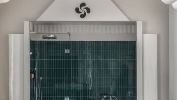A modern bathroom with a glass shower enclosure, a visible logo on the wall, and a towel rack.
