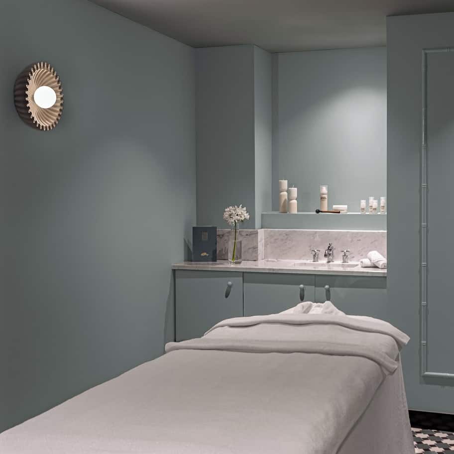 A minimalist bathroom with a single bed, a mirror, and a sink.