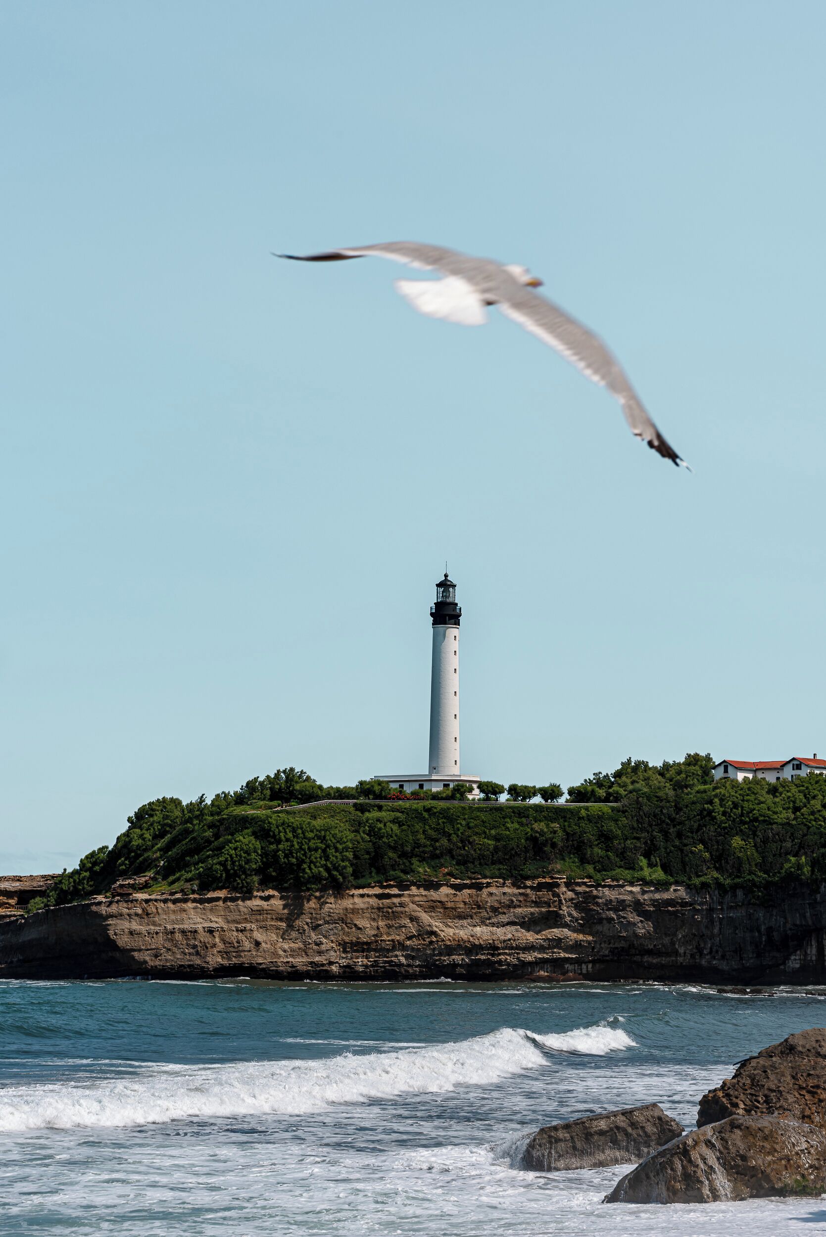 A lighthouse on a rocky coastline with waves crashing against the shore.