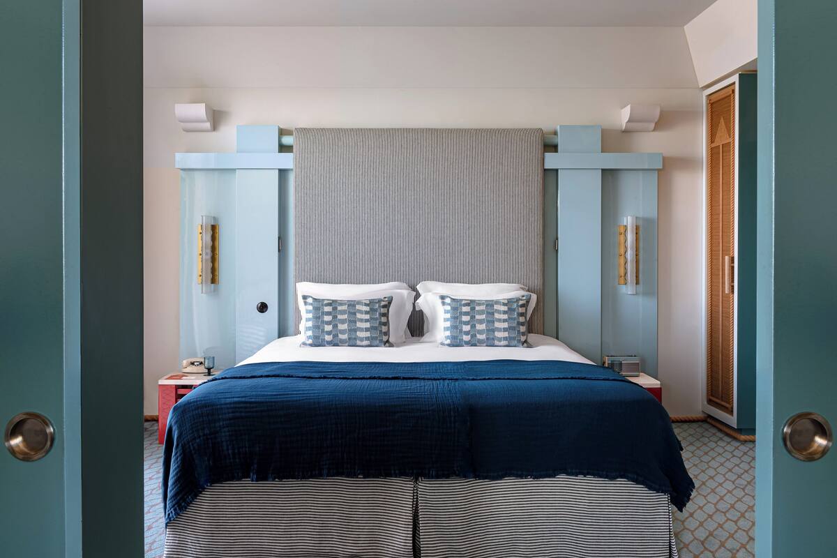 A bedroom with a bed, a nightstand, a bedside table, and a wardrobe.