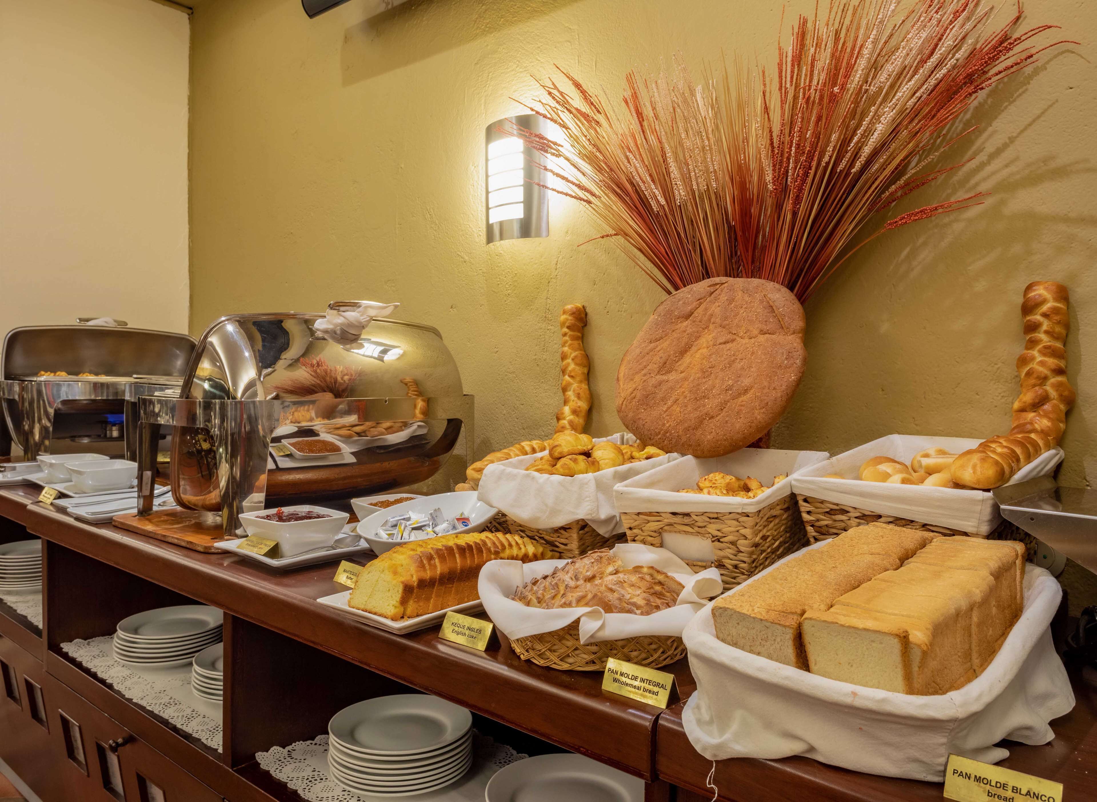 A buffet with various breads and pastries, including a loaf of English cake and a wholemeal bread.