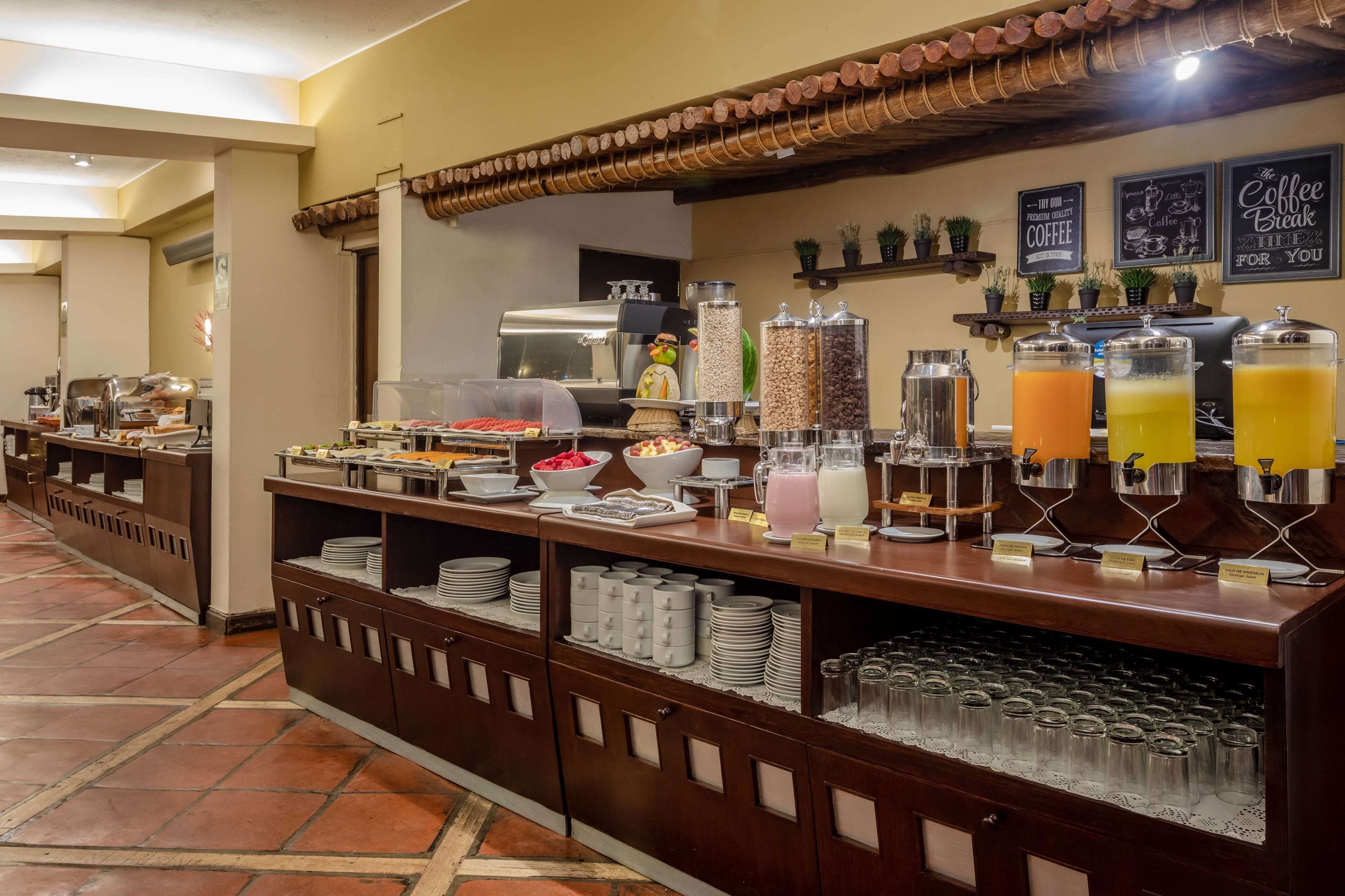 A buffet setup with various food items, a coffee machine, and a juice dispenser.