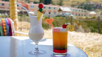 Dos bebidas sobre una mesa con vistas a edificios al fondo.