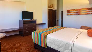 A hotel room with a bed, a TV on a dresser, a wardrobe, and a painting on the wall.