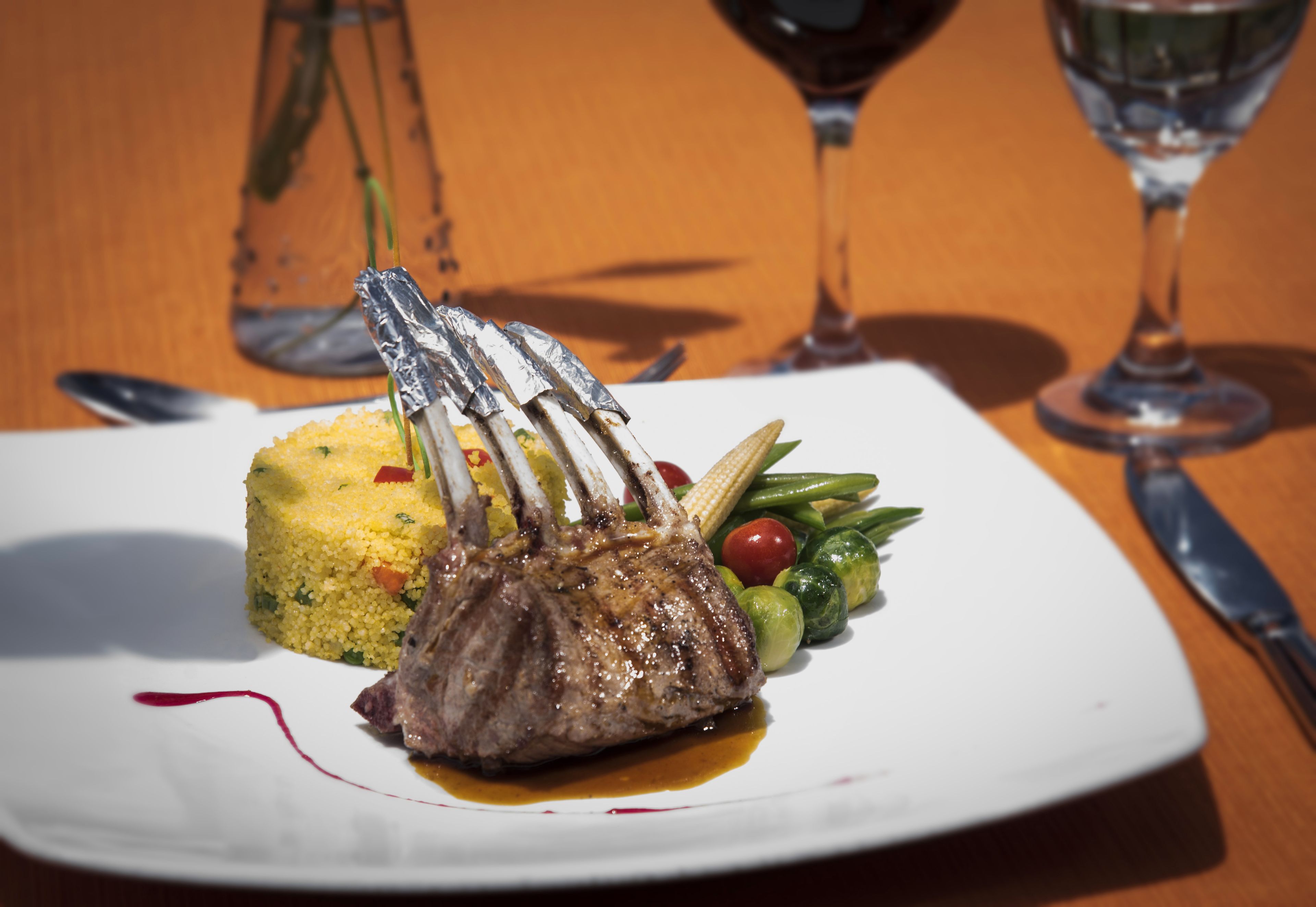 A plate with a lamb chop, couscous, and vegetables.