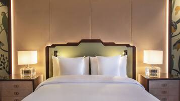 Een hotelkamer met een groot bed, twee nachtkastjes met lampen en een hoofdeinde met ingebouwde verlichting.