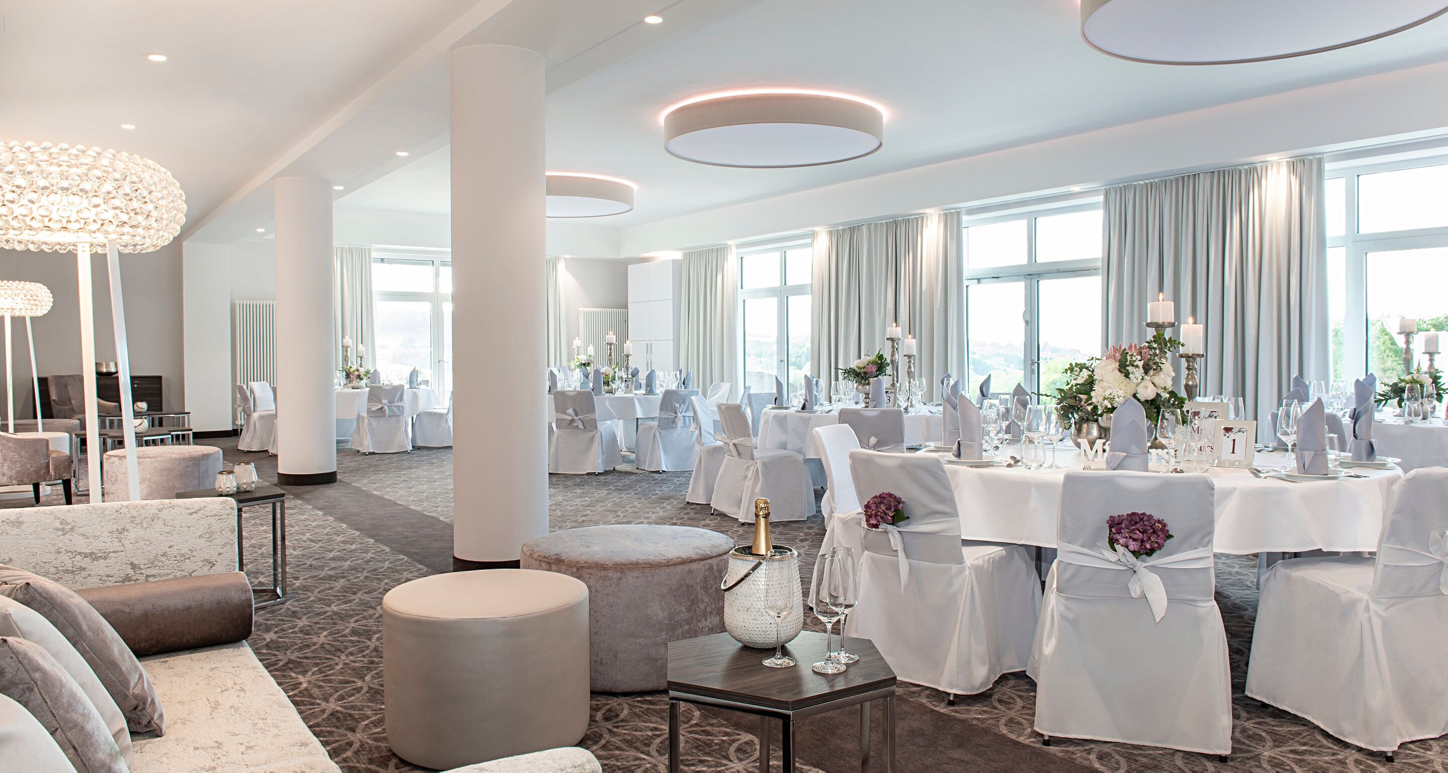 Un hall d’hôtel spacieux, doté de nombreux espaces de détente, de grandes fenêtres et d’un décor élégant.