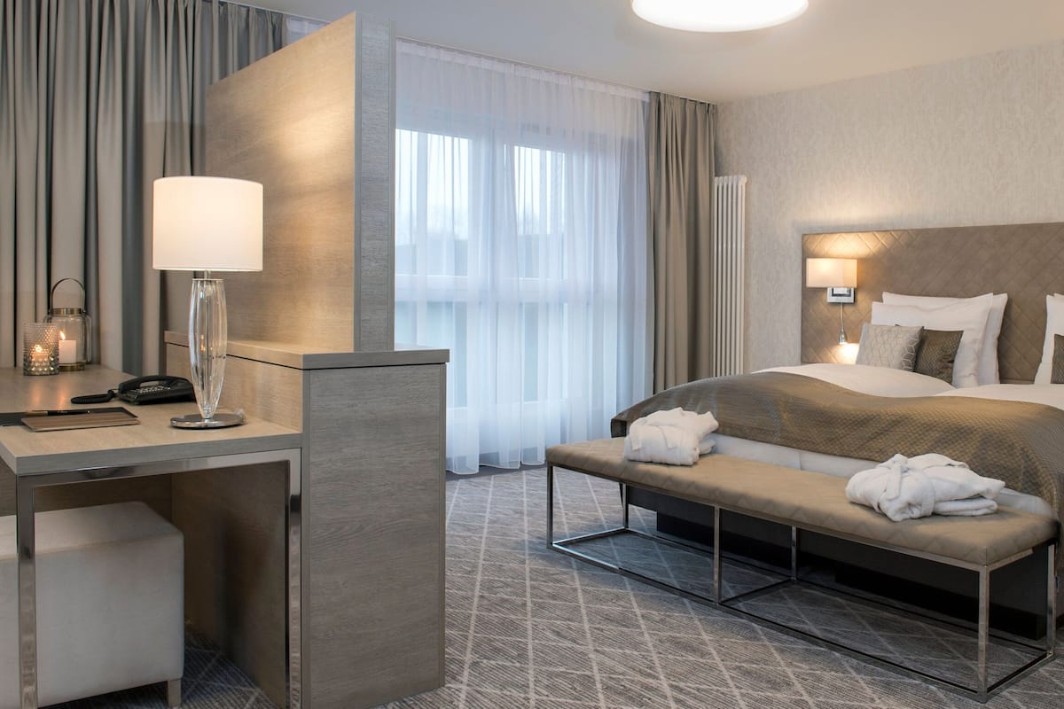 Una habitación de hotel moderna con una cama grande, mesitas de noche, un escritorio y un banco.