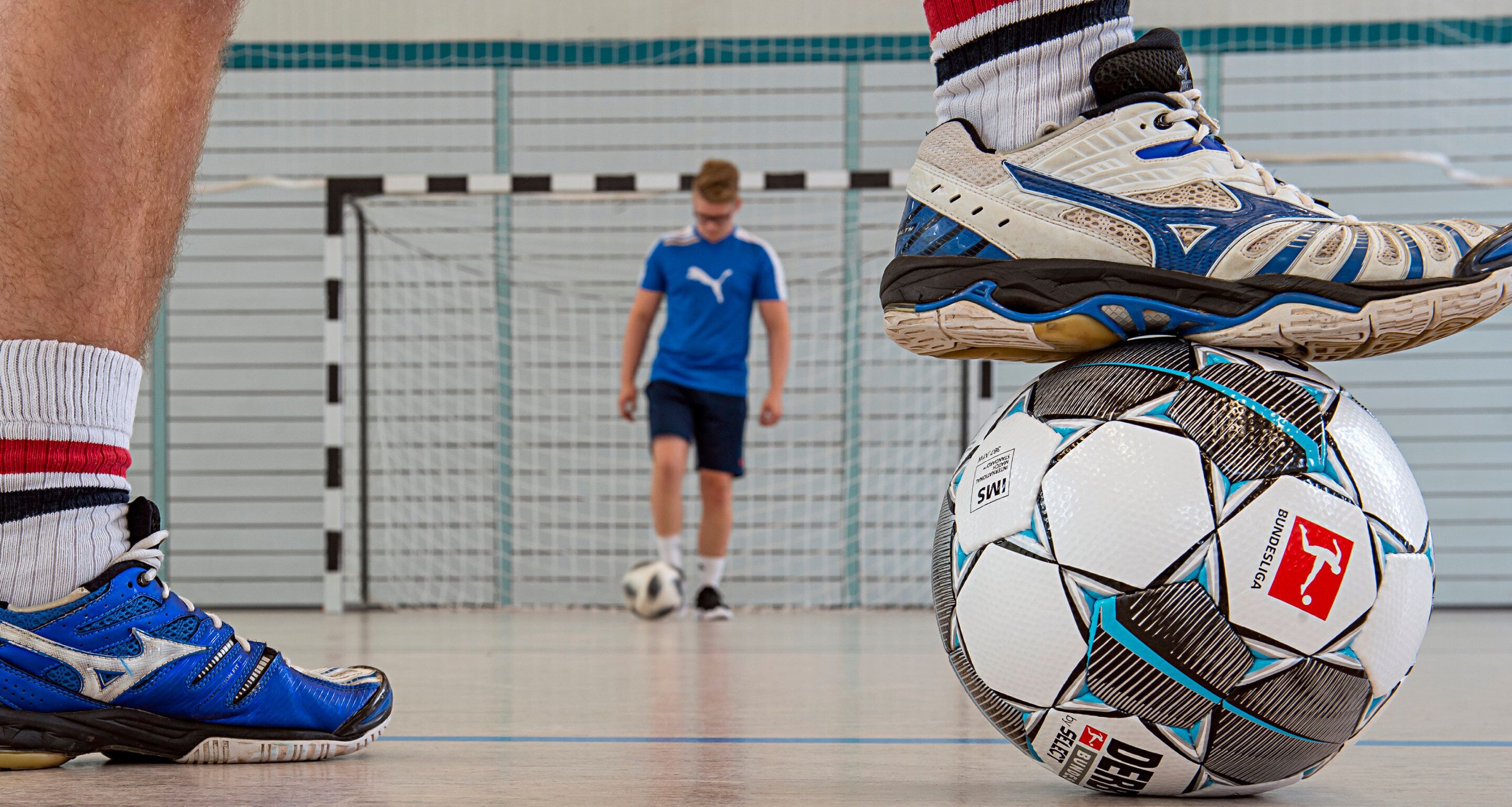 A close-up of a soccer ball with visible branding and a person balancing it on their foot.