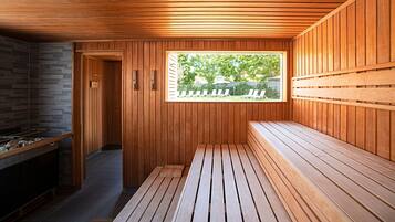 A sauna with wooden benches, a stone wall, and a window overlooking a backyard.