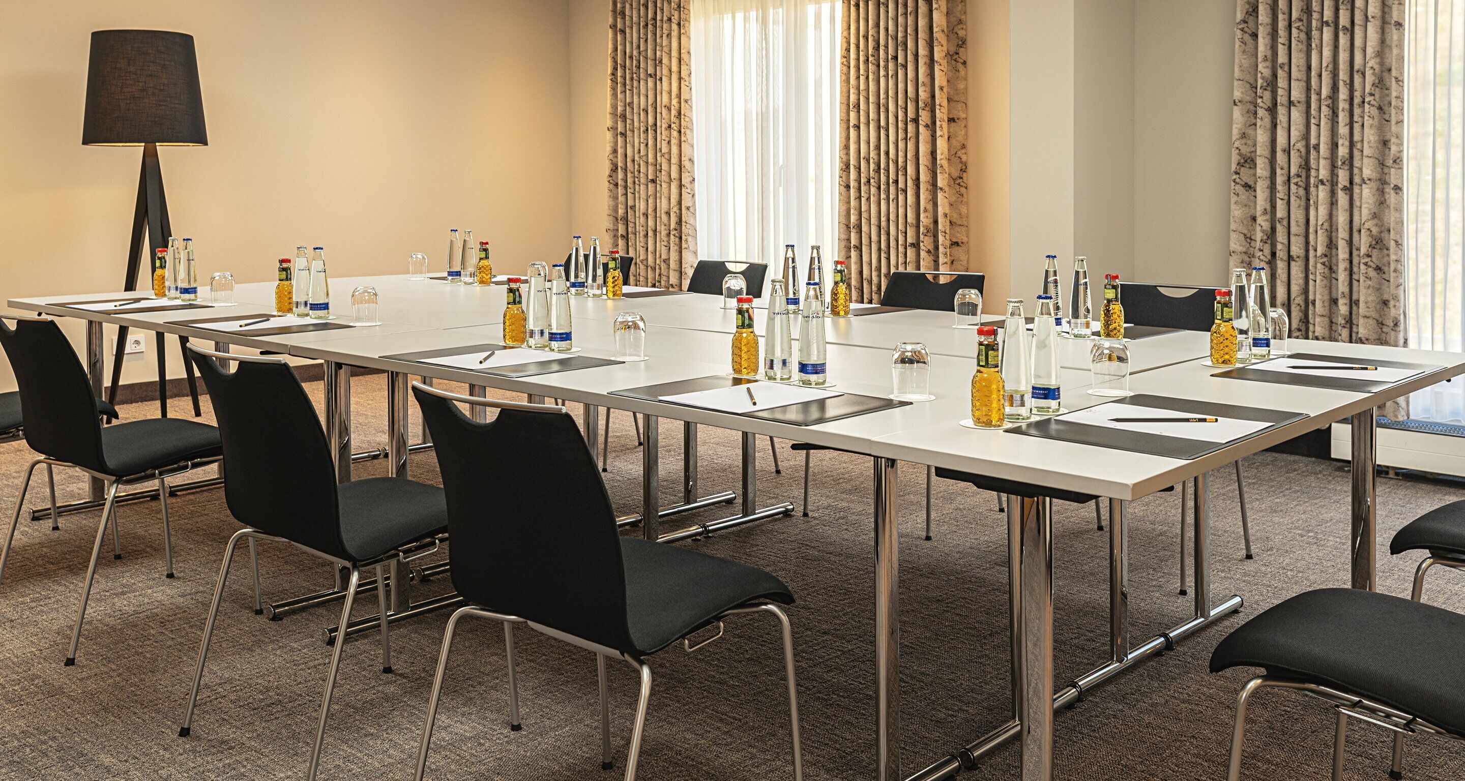A conference room with a long table, black chairs, and water bottles.