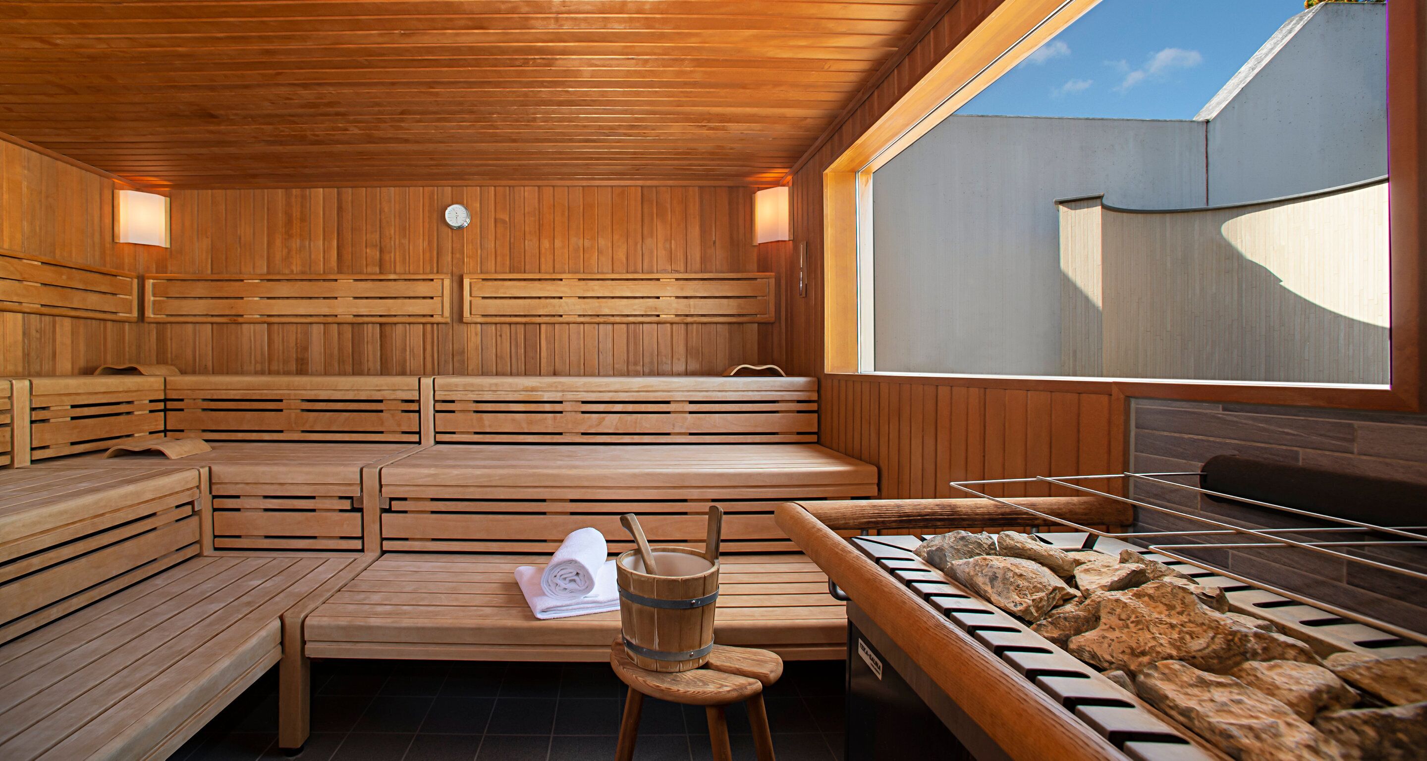 A sauna with wooden benches, a towel, and a stone basin.