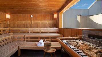 A sauna with wooden benches, a towel, and a stone basin.