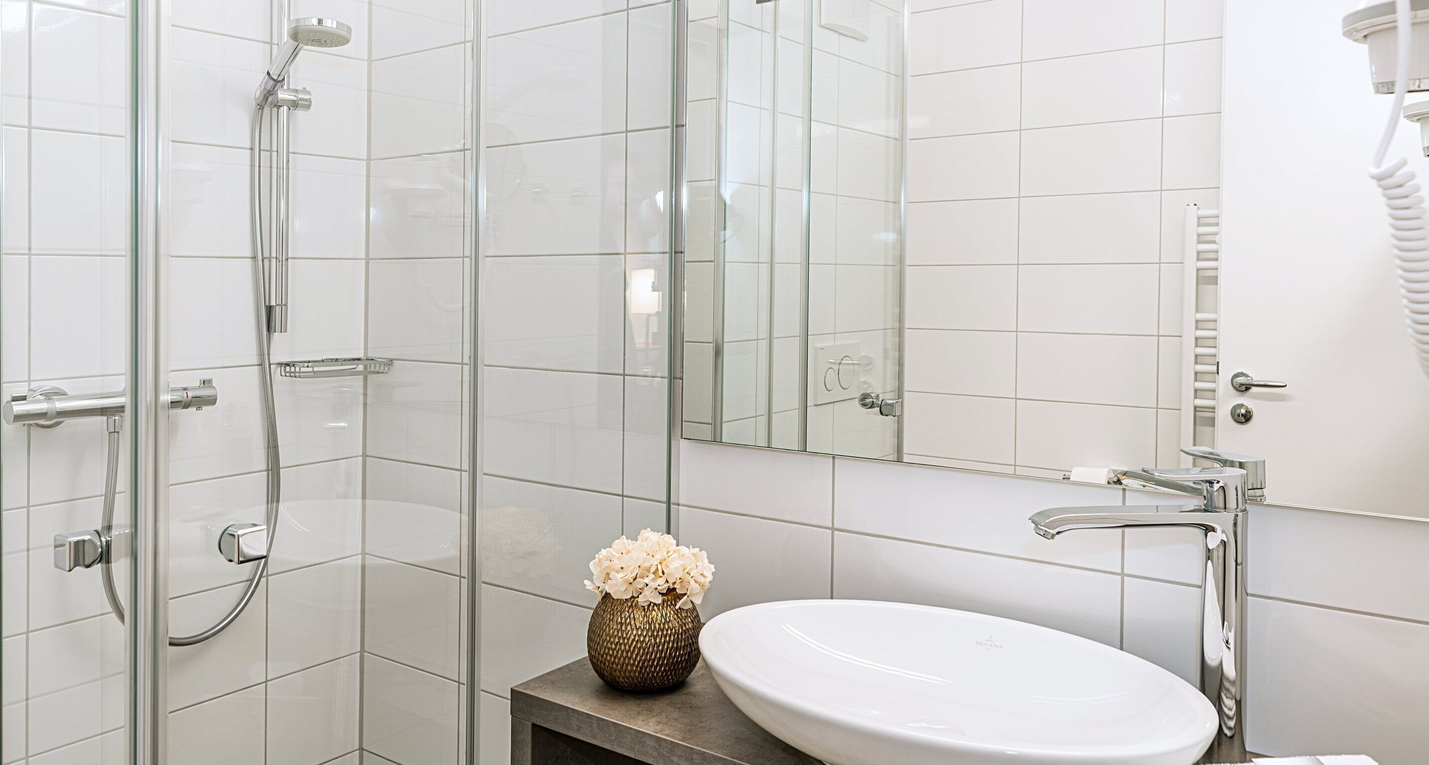 Un baño moderno con cabina de ducha de vidrio, un lavabo blanco y un espejo.