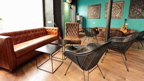 A modern lounge area with a leather sofa, a tufted armchair, and wicker chairs. - Arty Paris Porte de Versailles by River - Hostel (Paris)