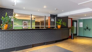 A reception area with a brick wall, potted plants, and a reception desk.