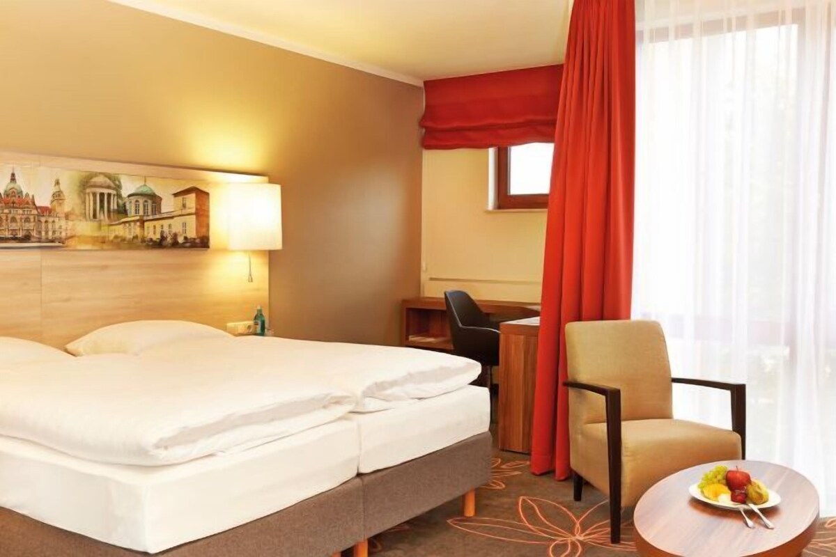Een hotelkamer met een bed, een bureau, een stoel en een ronde tafel met fruit.
