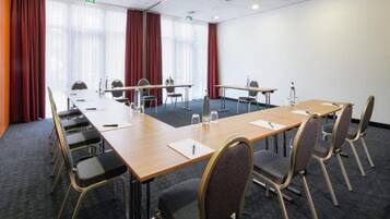 A conference room with a long table, chairs, and a carpeted floor.
