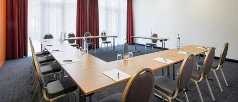 A conference room with a long table, chairs, and a carpeted floor.