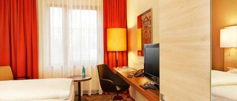 Une chambre d’hôtel avec deux lits, un bureau avec un ordinateur, une chaise et un téléviseur.
