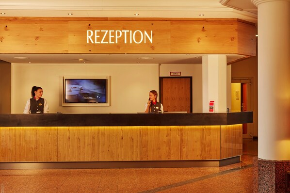 A reception area with a wooden reception desk, a television mounted on the wall, and a sign above the desk that reads "RECEPTION".