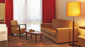Habitación de hotel con sofá, sillón y una mesa con fruta.