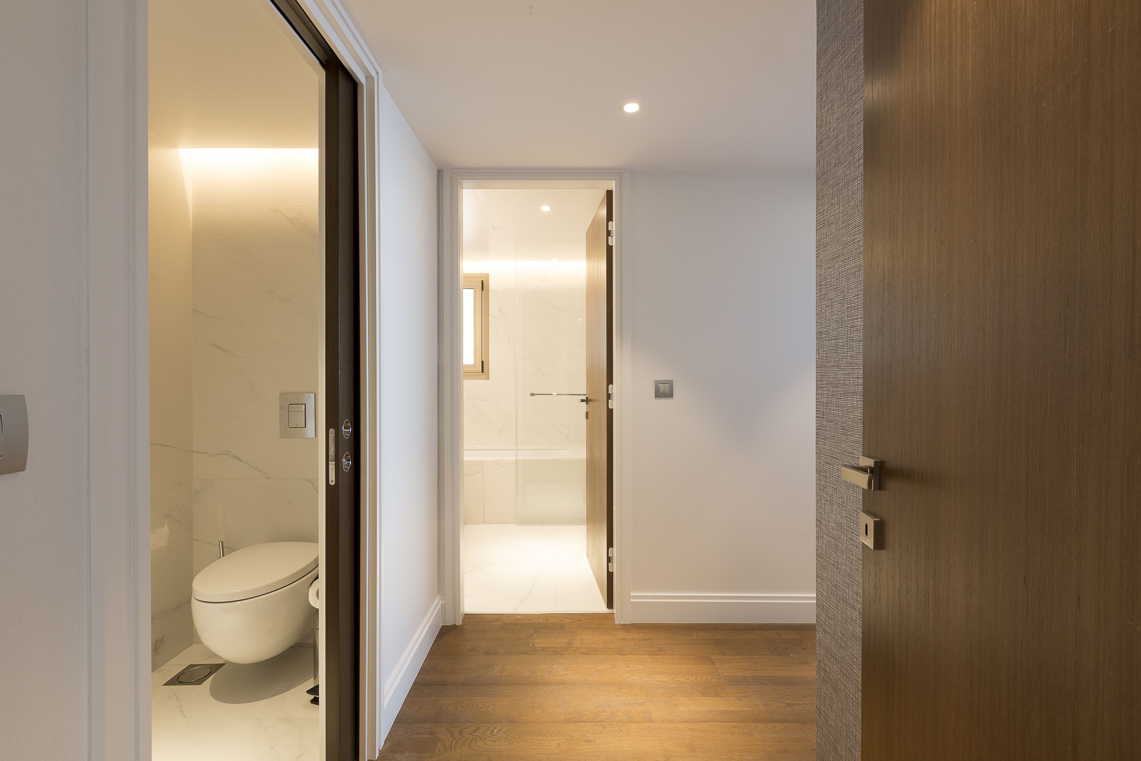 A modern bathroom with a toilet, a shower, and a wooden floor.