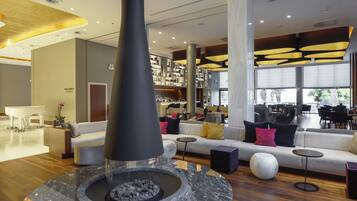 A modern lobby with a central fire feature, seating areas, and a visible reception desk.
