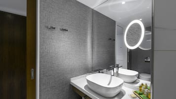 Un bagno moderno con due lavandini, un grande specchio e una luce circolare sopra lo specchio.