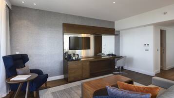 A modern living room with a sofa, a coffee table, a TV, and a wooden bar area.