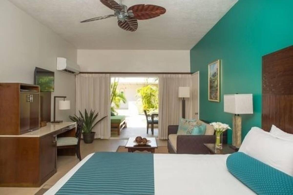 A hotel room with a bed, desk, chair, and a view of the outdoors.