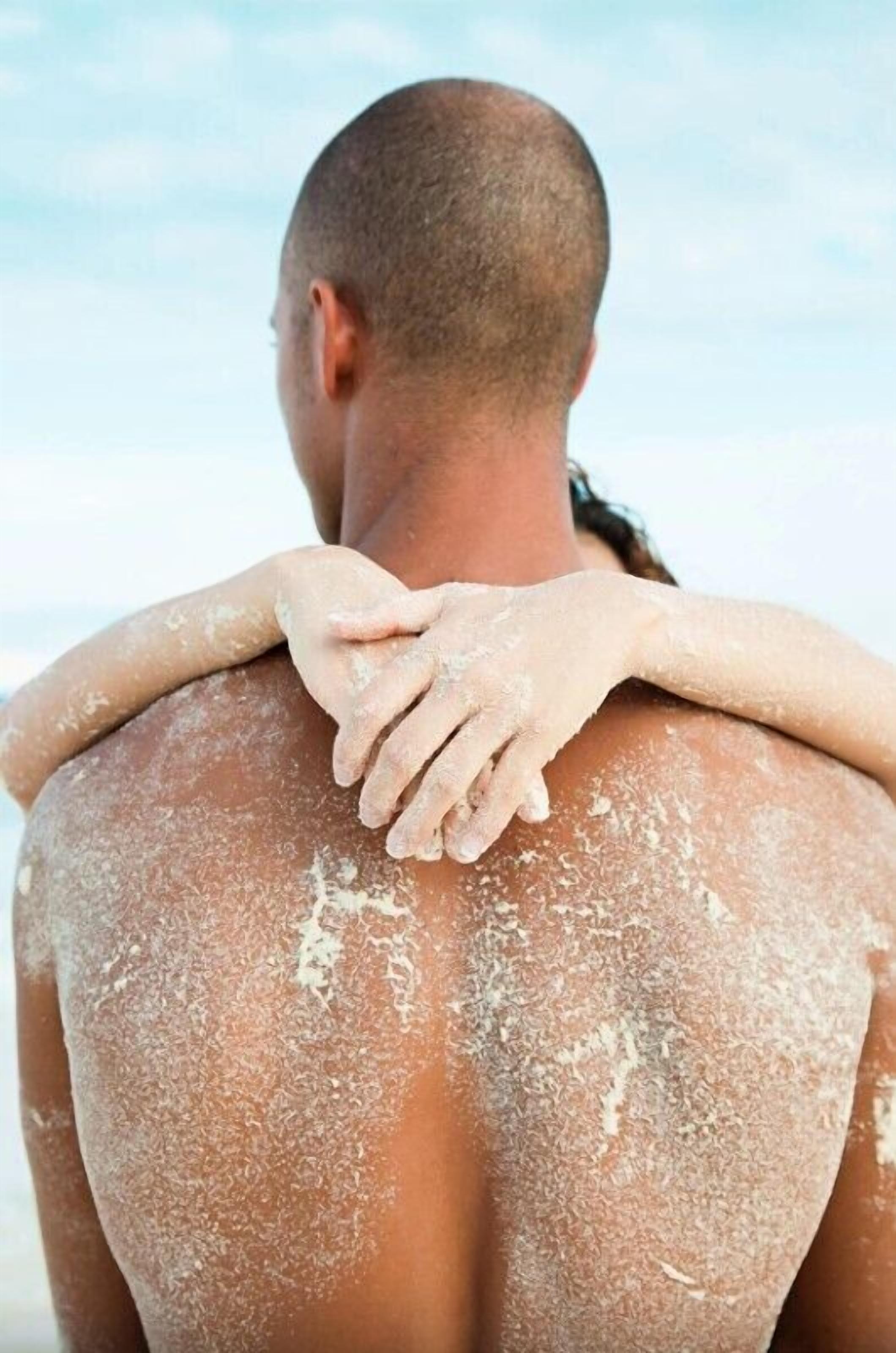 A person with their back to the camera, another person’s hands placed on their shoulders.