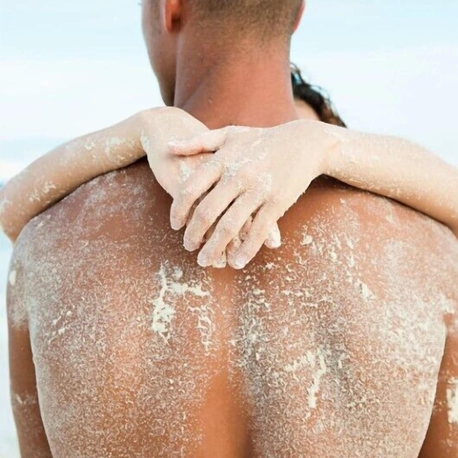 A person with their back to the camera, another person’s hands placed on their shoulders.