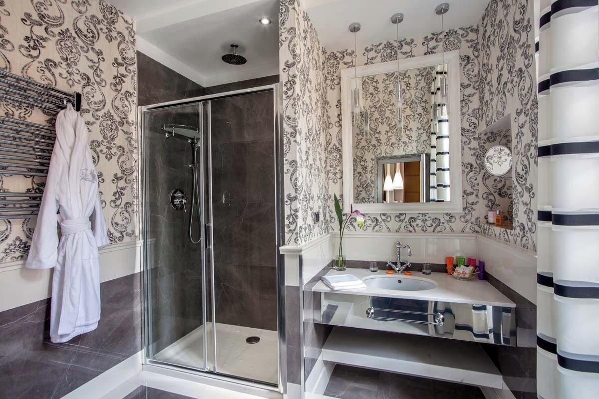 A modern bathroom with a glass shower, a white sink, and a large mirror.