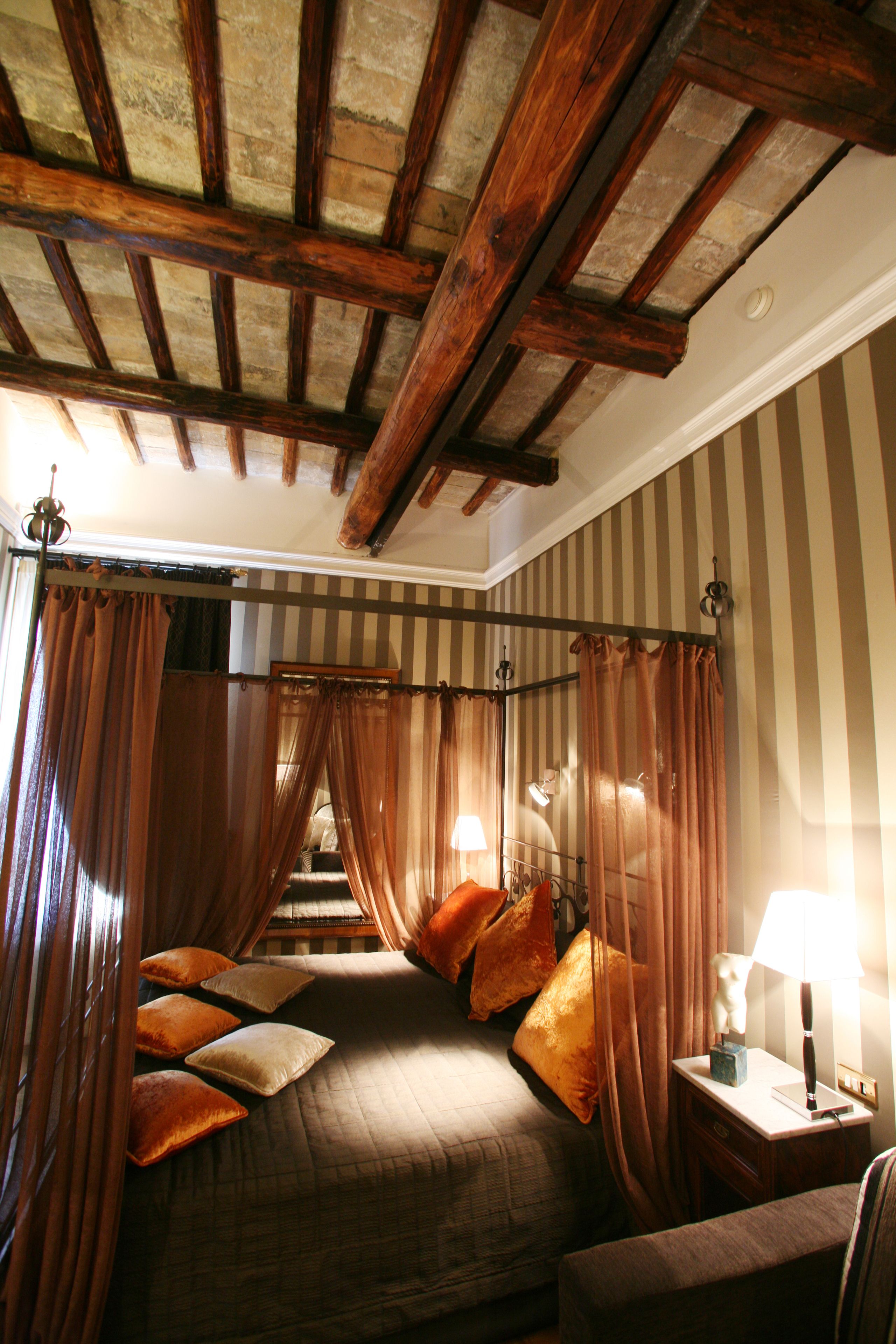 Une chambre avec un lit, des rideaux, une table de chevet et une lampe.