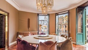 A round dining table with a white top, surrounded by six velvet chairs in various colors. - The Inn at the Spanish Steps (Rome)