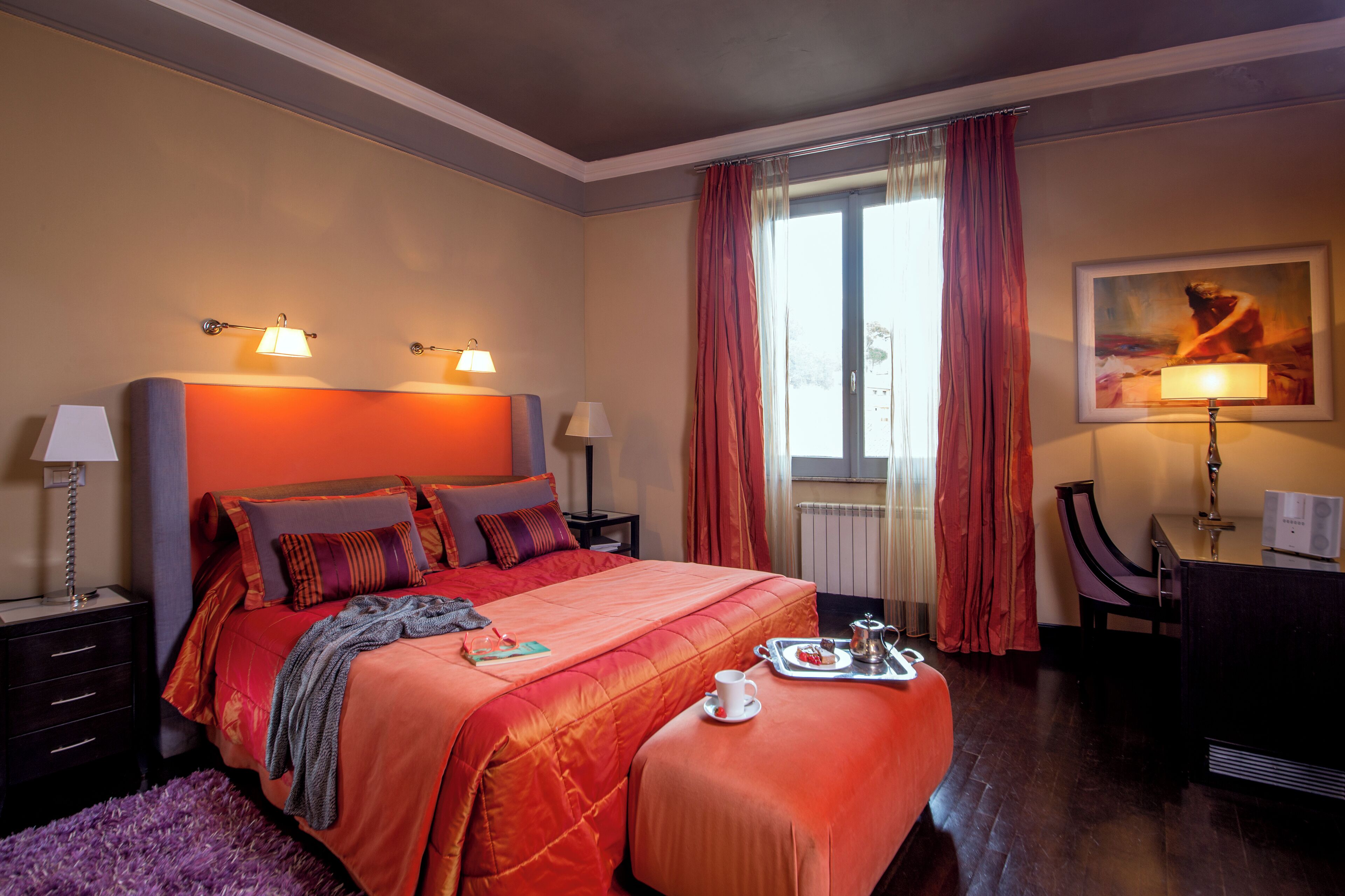 Habitación de hotel con una cama grande, dos lámparas de noche, un escritorio con silla, una ventana con cortinas y un cuadro en la pared.