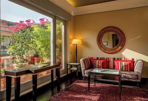 A living room with a sofa, a coffee table, a lamp, and a large mirror on the wall. - The Inn at the Spanish Steps (Rome)